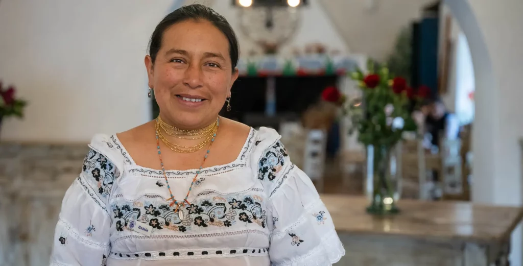 Host in traditional Otavalo dress welcoming guests at Hacienda Pinsaquí