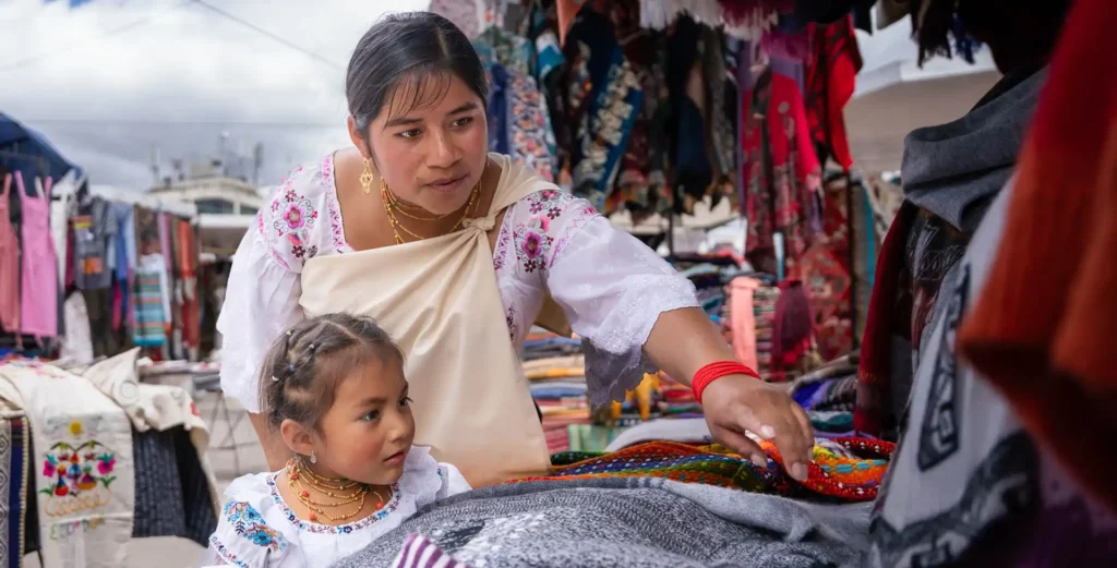 Otavaleña woman and her daughter at a craft stall in the Otavalo market
