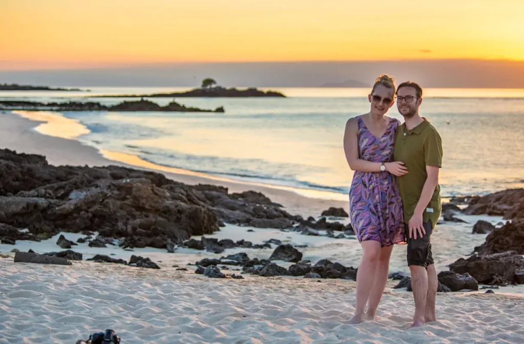 Couple watching the sunset over the Galapagos from a lava rock shoreline
