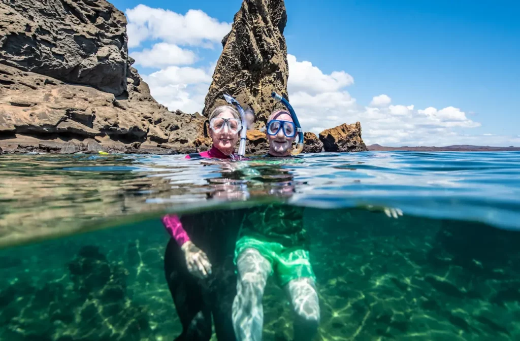 Snorkelers swimming with a sea turtle in clear Galapagos waters, Yacht Isabela II