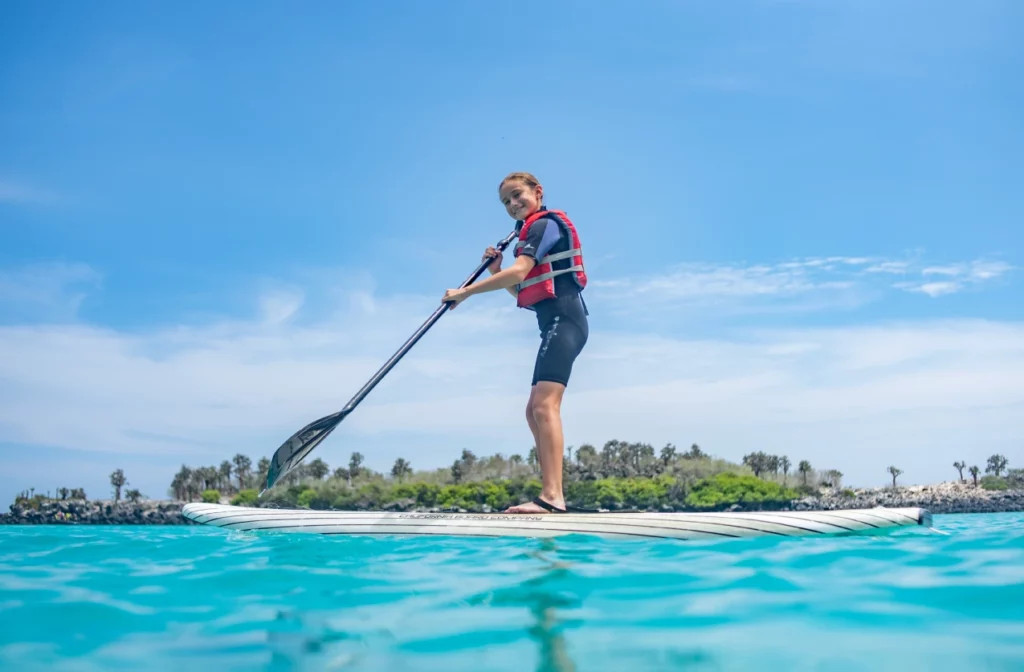 Los huéspedes practican paddleboarding en las tranquilas aguas de Galápagos junto al yate La Pinta.