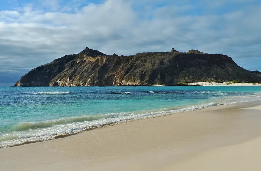 White sand beach at Cerro Brujo with dramatic volcanic headland and turquoise water, San Cristobal Island Galapagos