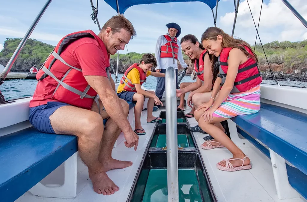 Family examining marine life through glass-bottom boat viewing panel at Gardner Bay, Española Island Galapagos