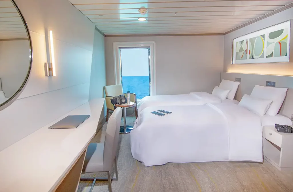 Camarote de lujo con dos camas individuales y ventana con vista al mar a bordo del yate La Pinta, Galápagos.