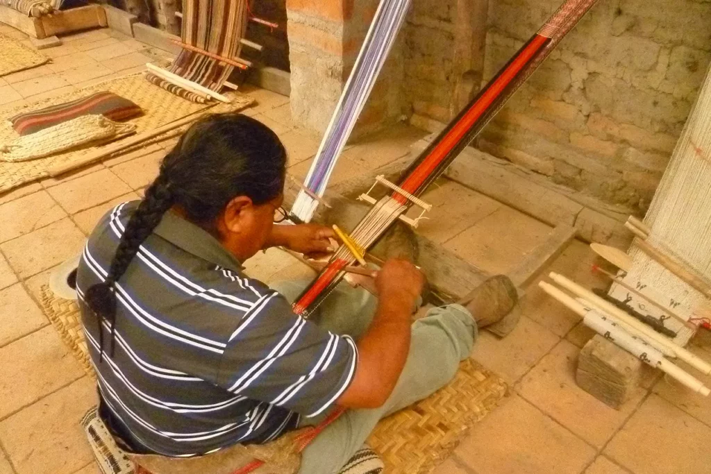 Tejedor trabajando en un telar de pedal en un taller textil de Peguche, Otavalo
