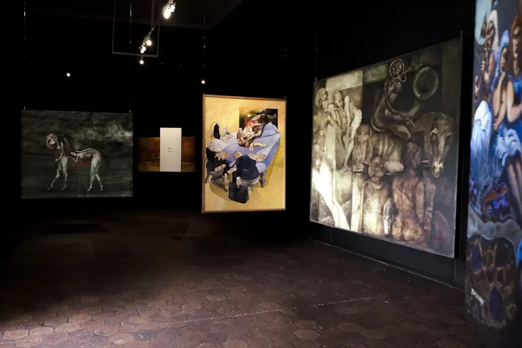 Dimly lit gallery room with large contemporary paintings in Cuenca