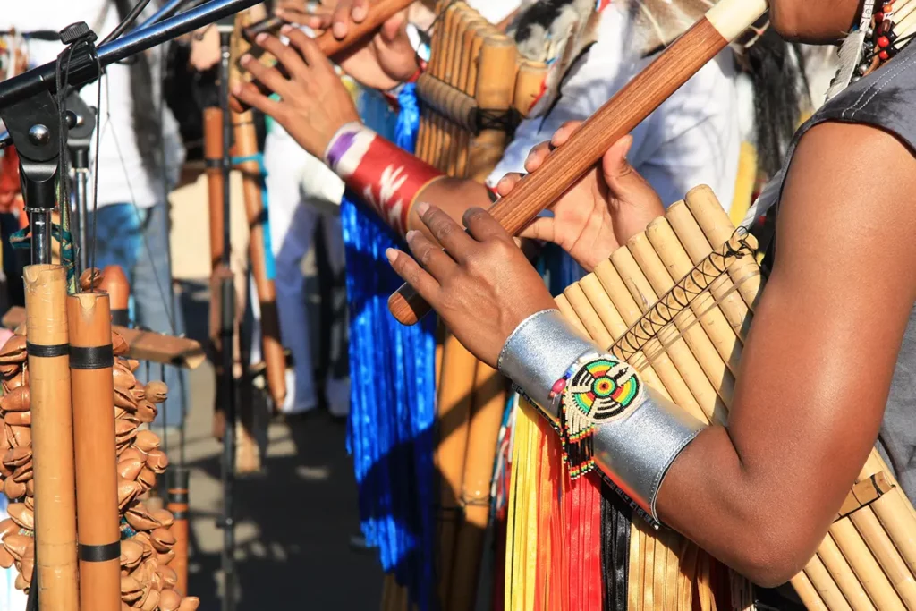 Musicians playing bamboo pan flutes in traditional Andean dress