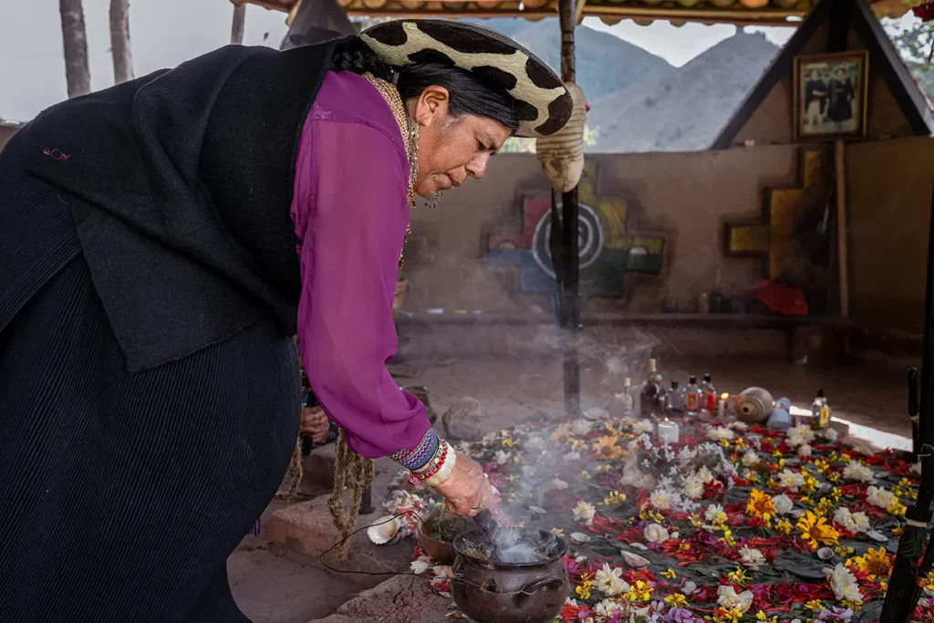 Saraguro woman performing a spiritual cleansing ritual with flowers and incense