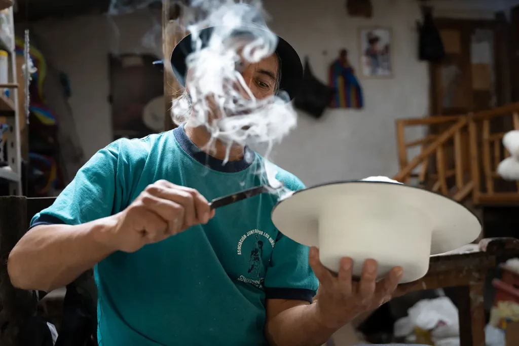 Artisan shaping a traditional Saraguro wool hat with steam