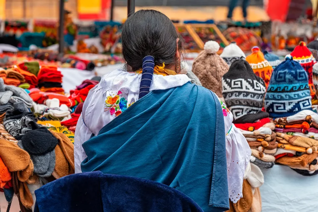 Woman browsing textiles and hats at the Otavalo market