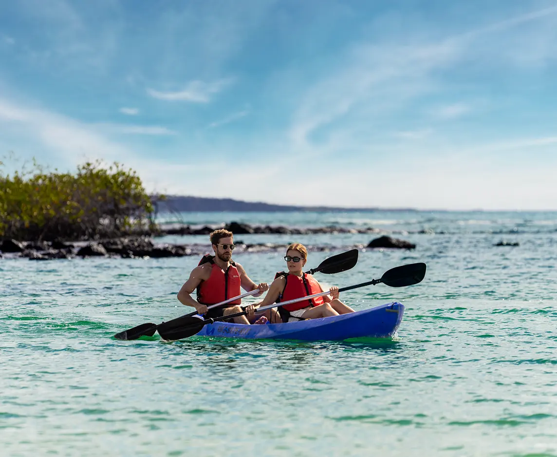 Pareja practicando kayak cerca de la costa durante un chárter en Galápagos